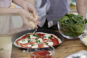 Couple preparing pizza in kitchen - FMKF002410