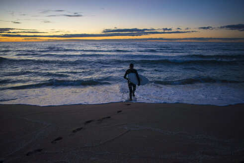 Spanien, Barcelona, Surfer bei Sonnenaufgang am Strand - SKCF000062