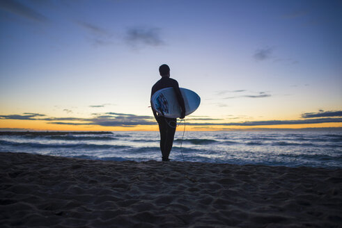 Spanien, Barcelona, Surfer bei Sonnenaufgang am Strand - SKCF000063