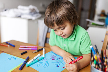 Little boy drawing on blue paper at home - VABF000178