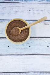 Wooden spoon and bowl of organic linseed on light blue wood - LVF004553