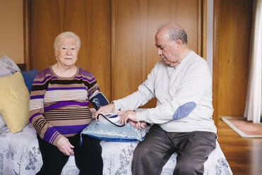 Senior man checking blood pressure of his wife at home - GEMF000741