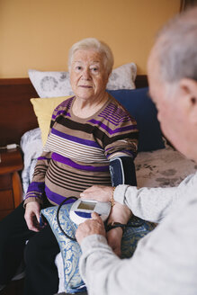 Ein älterer Mann kontrolliert den Blutdruck seiner Frau zu Hause - GEMF000742