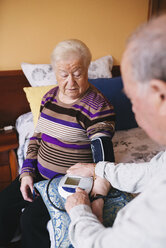 Ein älterer Mann kontrolliert den Blutdruck seiner Frau zu Hause - GEMF000743