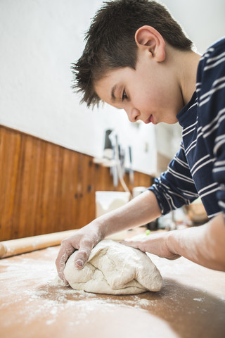 Junge knetet Teig auf der Küchenarbeitsplatte, lizenzfreies Stockfoto