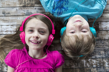 Porträt von Bruder und kleiner Schwester, die mit Kopfhörern Musik hören - SARF002579