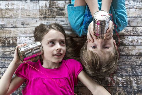 Portrait of brother and little sister playing with tin can phone - SARF002580
