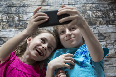 Porträt von Bruder und kleiner Schwester, die ein Selfie mit Smartphone machen - SARF002581