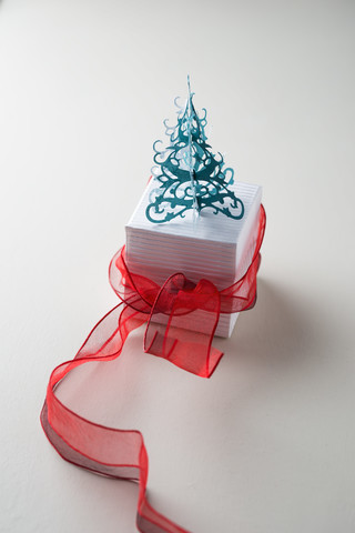 Geschenkkarton mit roter Schleife und Weihnachtsbaum, lizenzfreies Stockfoto