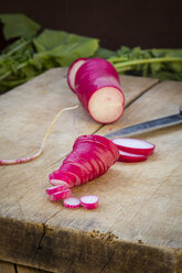 Sliced organic red radish on wooden board, close-up - LVF004569