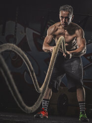 Älterer Crossfit-Sportler beim Training mit Seilen - MADF000830