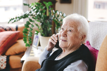 Portrait of smiling senior woman telephoning with smartphone at home - GEMF000750