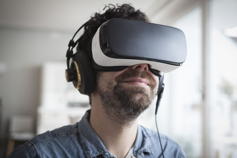 Smiling man wearing Virtual Reality Glasses and headphones stock photo