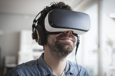Smiling man wearing Virtual Reality Glasses and headphones - RBF004090