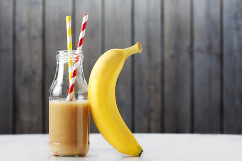 Glasflasche mit Bananensmoothie und eine Banane - CSF027240