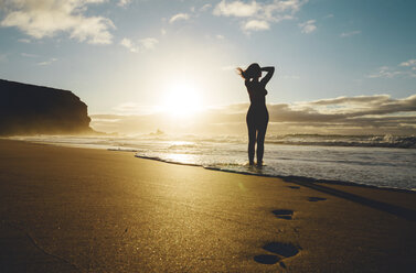 Woman standing on the beach at sunset - GEMF000761