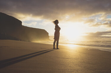 Spain, Fuerteventura, Woman standing on the beach at sunset - GEMF000762