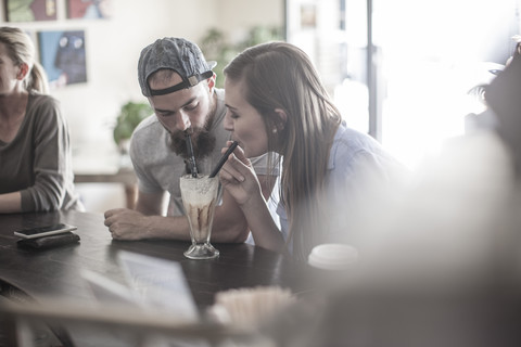Mann und Frau teilen sich einen Milchshake in einem Café, lizenzfreies Stockfoto