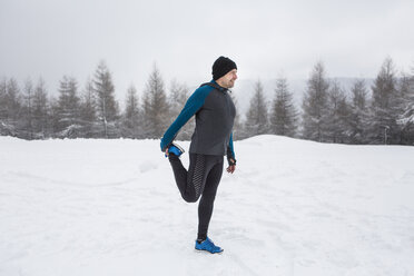 Mann beim Aufwärmen für einen Langlauf im Winter - HAPF000245