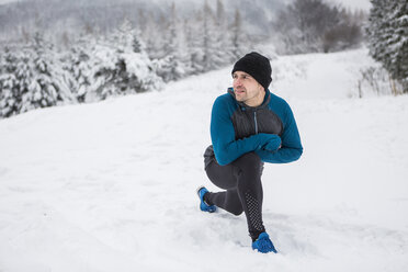 Mann beim Aufwärmen für einen Langlauf im Winter - HAPF000246