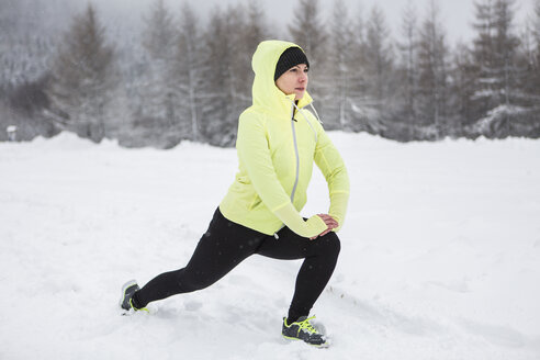 Frau beim Aufwärmen für einen Langlauf im Winter - HAPF000252