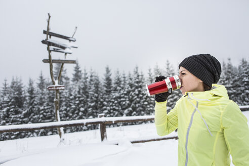 Frau trinkt im Winter ein heißes Getränk aus einer Thermoskanne - HAPF000255