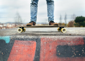 Legs of young man standing on his skateboarder - MGOF001476