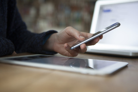 Frau am Tisch mit Smartphone, lizenzfreies Stockfoto