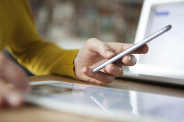 Woman at table using smartphone - RBF004099