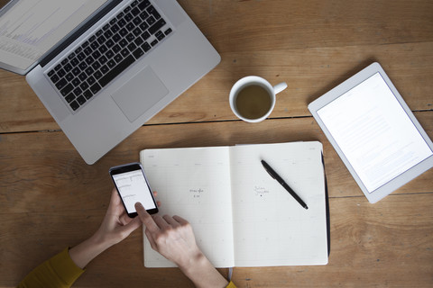 Woman at wooden table using smartphone stock photo