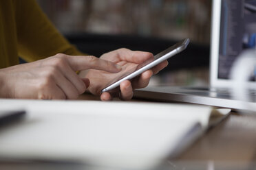 Woman at table using smartphone - RBF004104