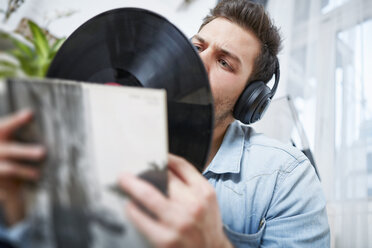 Young man wearing headphones looking at record - SEGF000461