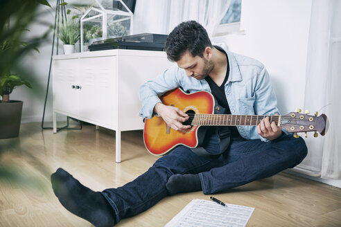 Junger Mann sitzt auf dem Boden und spielt Gitarre - SEGF000469