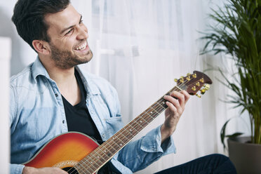 Happy young man playing guitar - SEGF000471