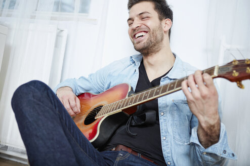 Happy young man playing guitar - SEGF000473