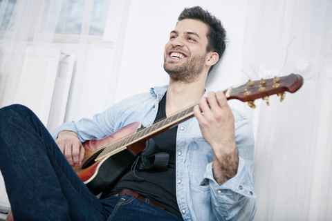 Glücklicher junger Mann spielt Gitarre, lizenzfreies Stockfoto