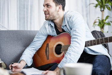 Junger Mann mit Gitarre komponiert ein Lied - SEGF000476