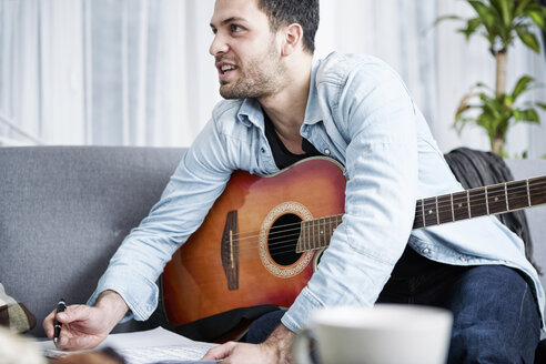 Junger Mann mit Gitarre komponiert ein Lied - SEGF000476