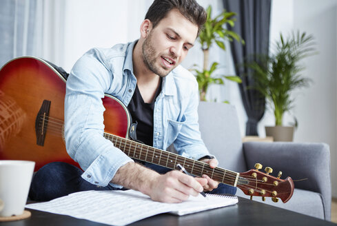 Junger Mann mit Gitarre komponiert ein Lied - SEGF000477