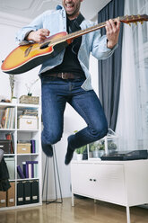 Begeisterter junger Mann, der zu Hause Gitarre spielt - SEGF000480