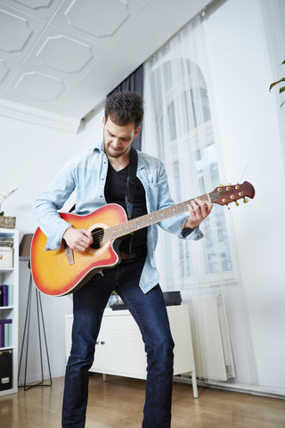 Junger Mann spielt zu Hause Gitarre, lizenzfreies Stockfoto