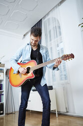 Young man at home playing guitar - SEGF000481