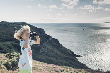 Frankreich, Bretagne, Atlantik, Junge an der Küste schaut durch ein Fernglas - MJF001773