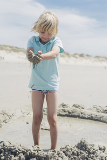 Frankreich, Bretagne, Finistere, Pointe de la Torche, Junge spielt mit Sand am Strand - MJF001787