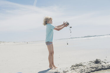 Frankreich, Bretagne, Finistere, Pointe de la Torche, Junge spielt mit Sand am Strand - MJF001788