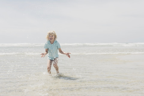 Frankreich, Bretagne, Finistere, Pointe de la Torche, Junge spielt im Wasser, lizenzfreies Stockfoto