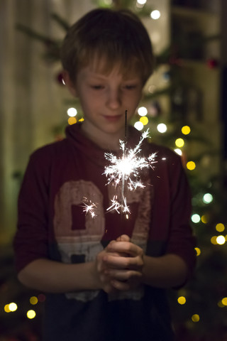 Junge hält Wunderkerze zur Weihnachtszeit, lizenzfreies Stockfoto