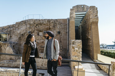 Spain, Tarragona, Young couple talking as they walk around the city - JRFF000451