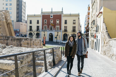 Spain, Tarragona, Young couple talking as they walk around the city - JRFF000452