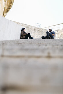Spanien, Tarragona, Städtereise, junges Paar im Gespräch, auf Stufen sitzend - JRFF000458
